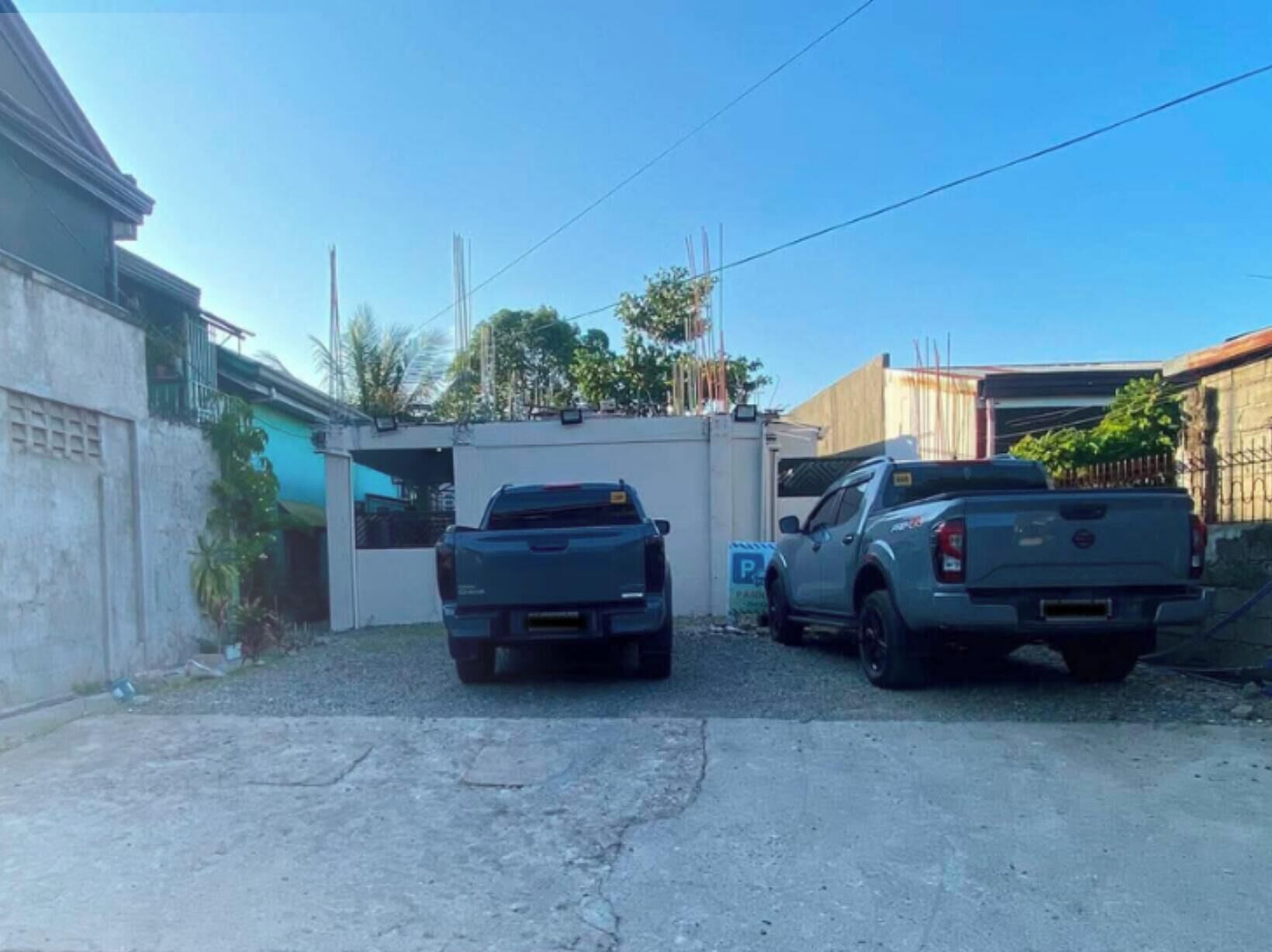A parking area with two pickup trucks parked in front of a building with a blue awning.