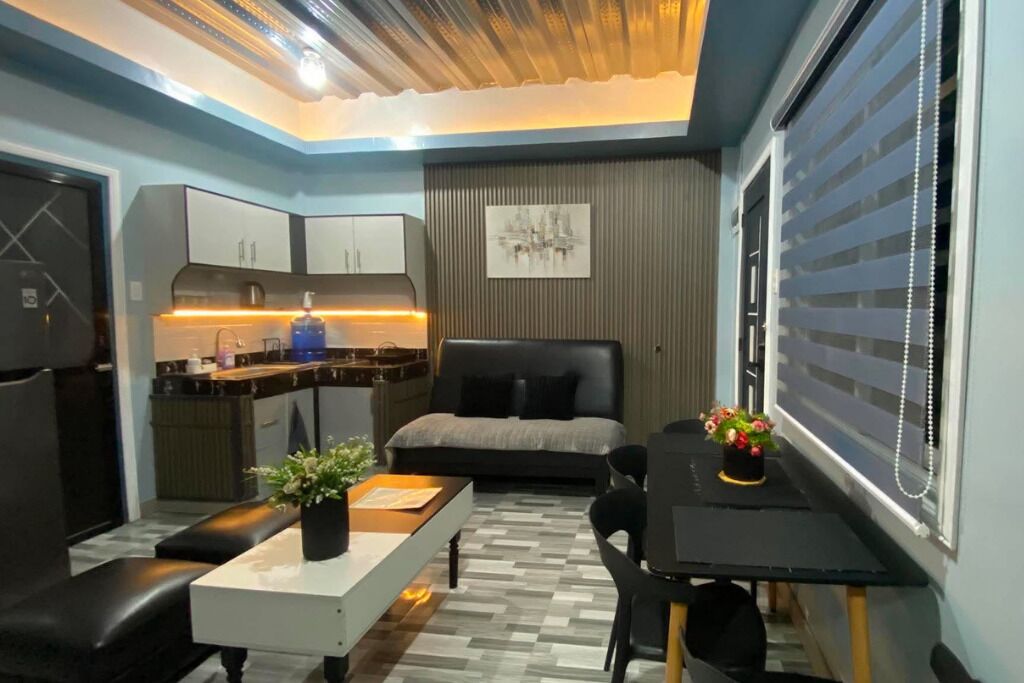 Een compact woongedeelte met een kitchenette, een bed, een eethoek en een raam met zonwering.