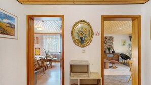 Quarto com teto de madeira, um quadro emoldurado, uma mesa pequena e uma cadeira.