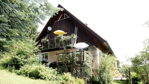 Uma casa de madeira com varanda, cercada por vegetação.