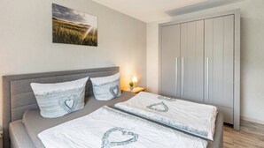 A bedroom with a bed, pillows, a nightstand, a lamp, a wardrobe, and a wall-mounted picture. - Apartment 'Fischer' with Mountain View, Private Terrace and Wi-Fi (Diemelsee)