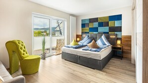 Un dormitorio moderno con una cama grande, una silla verde brillante, vistas a un paisaje urbano y una pared con arte abstracto y colorido.