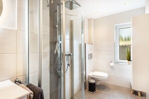Ein modernes Badezimmer mit Duschkabine aus Glas, Toilette und Waschbecken.