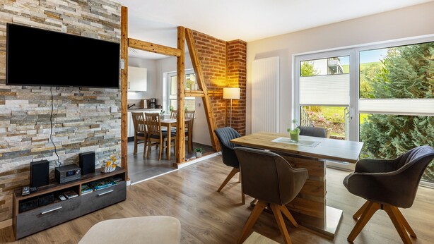 Una sala moderna con pared de piedra, mesa de comedor de madera y sillas.