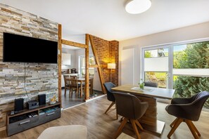 Ein modernes Wohnzimmer mit Steinwand, Holztisch und Stühlen.