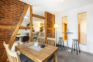 Un comedor con mesa de madera, sillas y pared de ladrillo.
