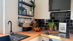 Une cuisine moderne avec un évier noir, un plan de travail en bois et un four encastré.