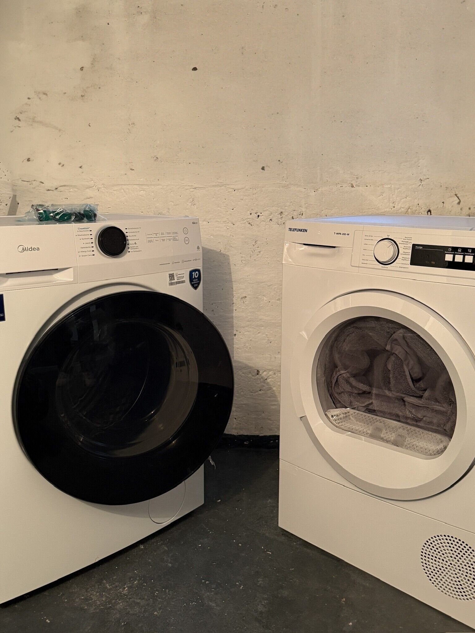 Twee voorladers, waarvan één een zwarte deur heeft en de andere een witte, tegen een effen muur.