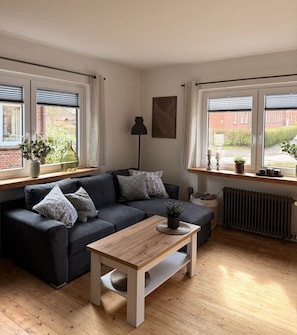 A modern living room with a grey sofa, a wooden coffee table, and a radiator.