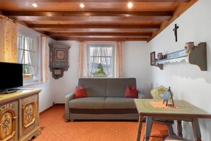 A cozy room with a sofa, a television, a wooden cabinet, and a table with a sign. - Room 'Nr 7' with Mountain View, Shared Terrace and Wi-Fi (Titisee-Neustadt)
