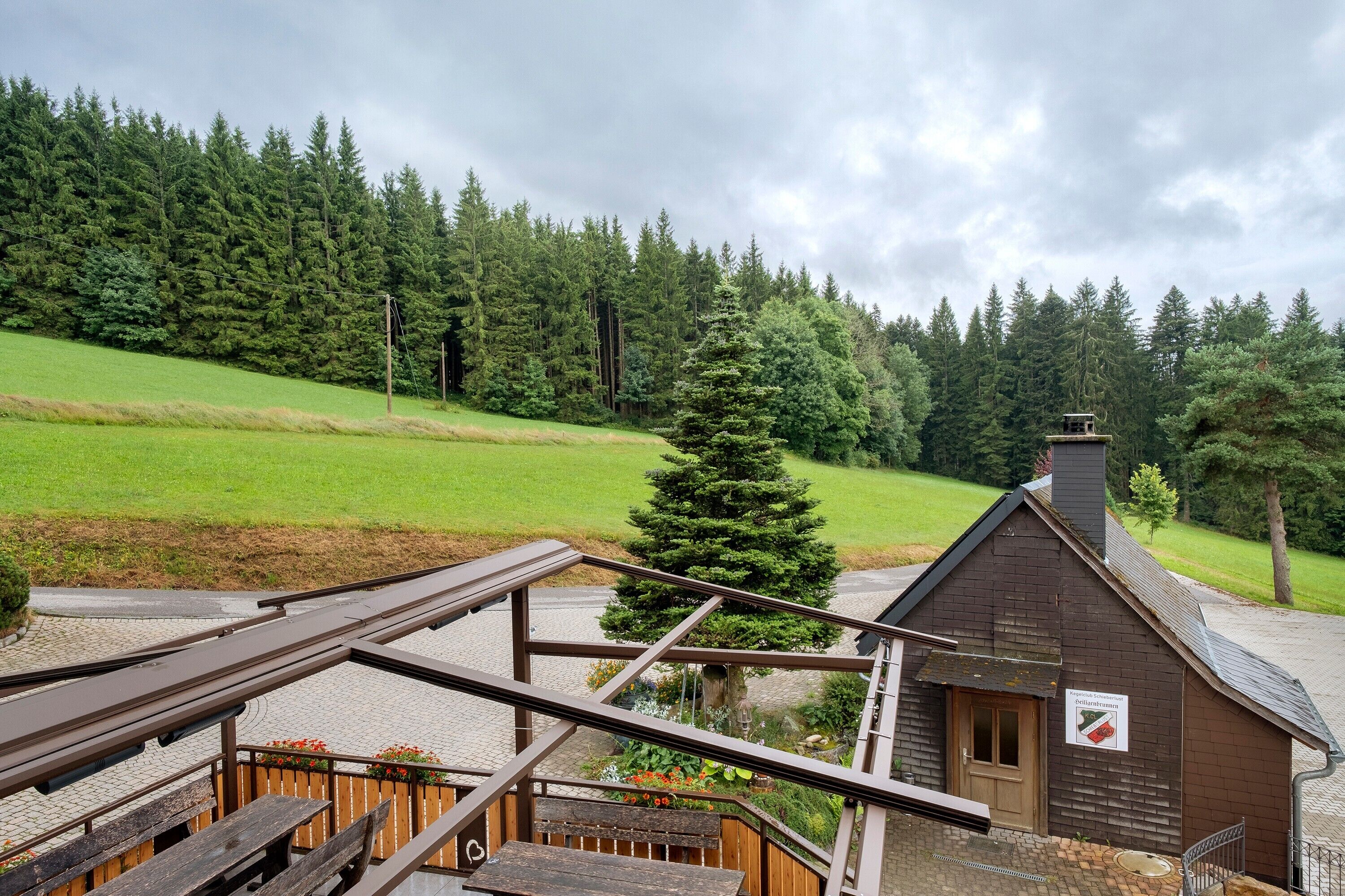 A wooden cabin with a sign indicating a restaurant, surrounded by a forested area.