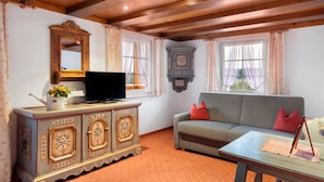 A room with a wooden ceiling, a sofa, a television on a cabinet, and a window with curtains. - Room 'Nr 7' with Mountain View, Shared Terrace and Wi-Fi (Titisee-Neustadt)