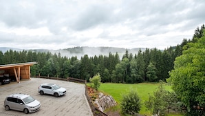 A parking area with three cars, a wooden building, and a view of a forested mountain range. - Room 'Nr 7' with Mountain View, Shared Terrace and Wi-Fi (Titisee-Neustadt)