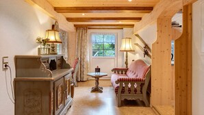 Een gezellige kamer met een houten plafond, een bank, een tafel en een kast.