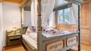 Een hemelbed met hemel, een nachtkastje met lamp en een raam met gordijnen.