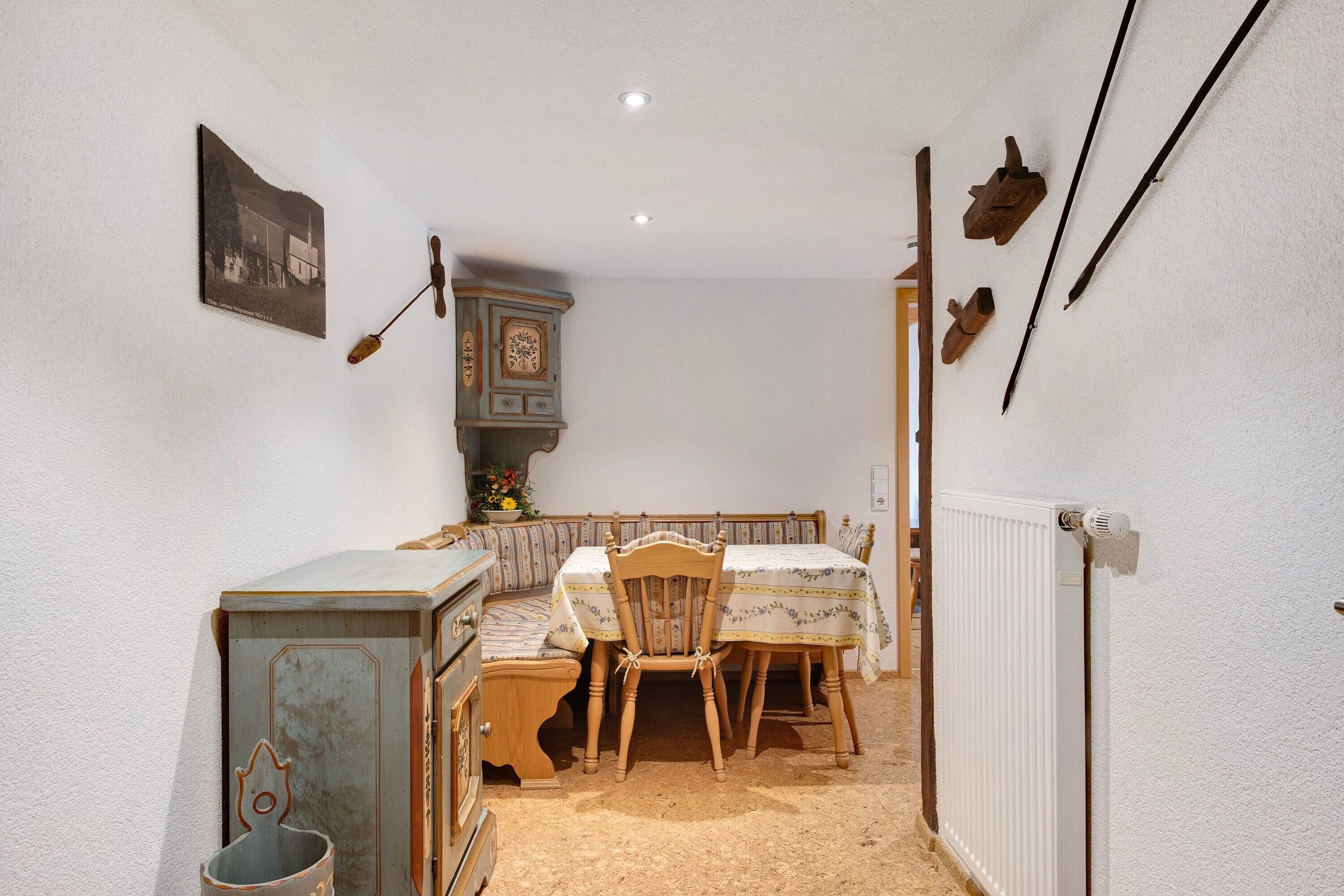 Une pièce étroite avec une table et des chaises en bois, un radiateur et un meuble ancien.
