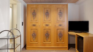 Quarto com guarda-roupa de madeira, televisão e cadeira de metal.