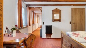 A room with a wooden bed, a small table with a vase of flowers, a mirror on the wall, and a door. - Room 'Nr 4' with Mountain View, Shared Terrace and Wi-Fi (Titisee-Neustadt)