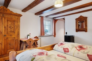 Une chambre à coucher avec un lit en bois, un bureau, une chaise, une armoire et une fenêtre avec des rideaux.