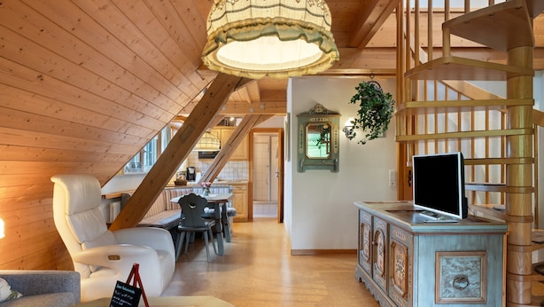 A wooden interior with a staircase, a dining area, and a television on a cabinet.
