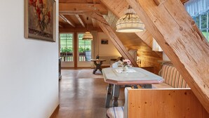 A wooden interior with a high ceiling, a dining table with chairs, and a bench.
