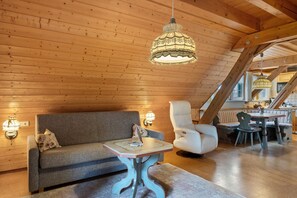 Une pièce chaleureuse avec un plafond en bois, un canapé, une table et une chaise.