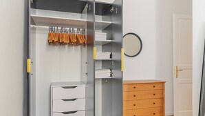 A walk-in closet with multiple shelves, a wooden dresser, and a mirror on the wall. - Blueground | Margareten, elevator, nr Naschmarkt (Vienna)