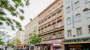 A street view with buildings, a 'Sweet Five' sign, and a 'Trauring Store' window. - Blueground | Margareten, elevator, nr Naschmarkt (Vienna)