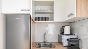 A modern kitchen with a stainless steel refrigerator, a sink, a coffee maker, and a Nespresso machine. - Blueground | Margareten, elevator, nr Naschmarkt (Vienna)