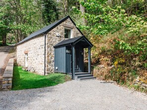 A stone building with a small porch and steps leading to a door.