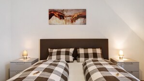 A bedroom with two beds, a headboard, bedside lamps, and a painting on the wall. - Holiday Apartment Mühlerain with Balcony (Heitersheim)