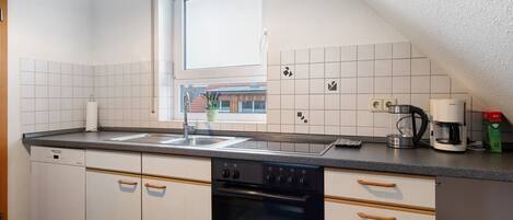 Una cocina con armarios blancos, un horno Bosch, una cafetera y un ventanal.