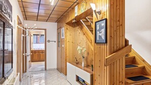 Un interior de madera con una escalera, una consola blanca y un cuadro en la pared.