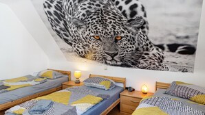 Un dormitorio con dos camas, un cuadro grande con estampado de leopardo en la pared y lámparas de noche.