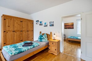 Une chambre à coucher avec un lit, une table de chevet, une armoire et un mur décoré de tableaux.