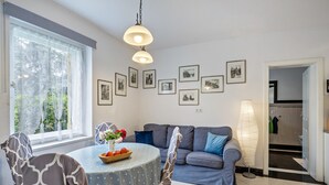 A dining area with a round table, chairs, a vase with flowers, and a sofa.