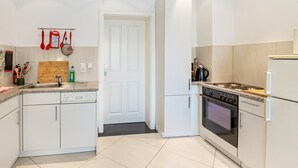 A modern kitchen with white cabinets, a dishwasher, a stove, and a refrigerator.