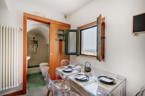 Un baño pequeño con ducha, inodoro y un comedor con mesa para dos.