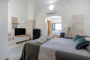 A bedroom with a bed, a TV, a desk, and a chair.