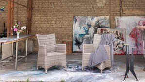 A room with two wicker chairs, a table with a vase of flowers, and abstract paintings on the walls. - Farmstead 'Vierseitenhof' with Private Pool, Private Terrace and Wi-Fi (Ziesar)