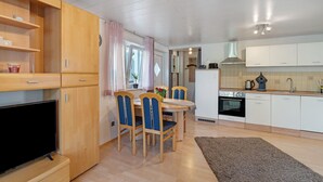 Una cocina moderna con armarios de madera, una mesa de comedor con sillas, un televisor y una isla de cocina.