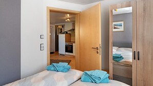 Un dormitorio con dos camas, un armario de madera y vistas a la cocina.