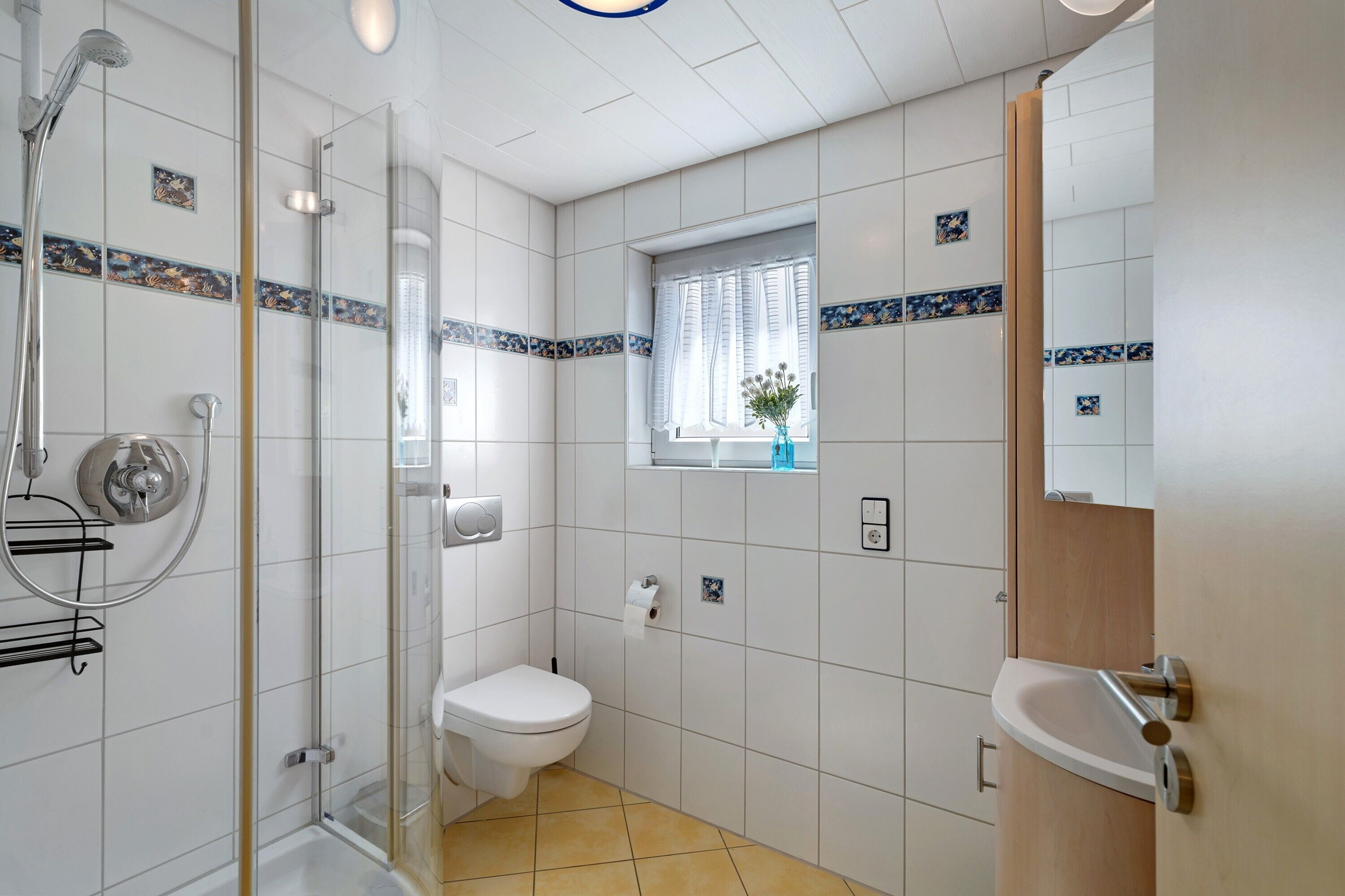 Une salle de bain avec douche, toilettes, lavabo et une fenêtre donnant sur un beau paysage.