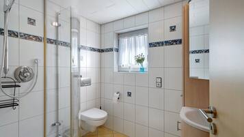 Une salle de bain avec douche, toilettes, lavabo et une fenêtre donnant sur un beau paysage.