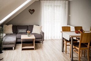 A cozy living room with a sofa, a coffee table, and a dining area with chairs and a table.