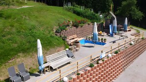 Eine Terrasse mit Holzbanken, einem Billardtisch und Sitzgelegenheiten im Freien.