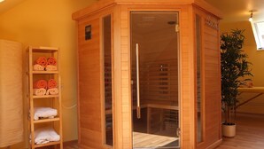 Ein Saunaraum mit Holzwänden, einer Glastür und einem Regal mit Handtüchern.