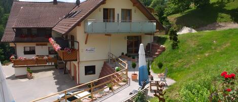 A two-story building with a balcony, outdoor seating, and a small garden area.