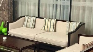 A modern living room with a beige sofa, striped pillows, and a dark wooden coffee table. - Campanile Jingdezhen Mperial Kiln Hotel (Jingdezhen)