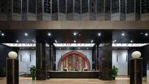 A reception area with a modern design, featuring a reception desk, a large arched window, and a decorative fountain. - Campanile Jingdezhen Mperial Kiln Hotel (Jingdezhen)